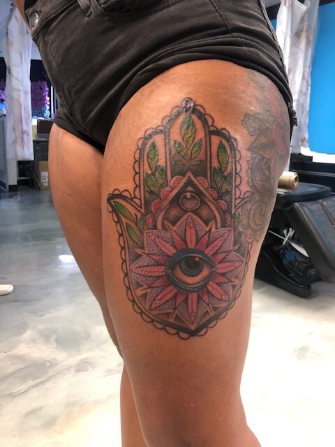 Thigh tattoo of a lotus hand with flowers