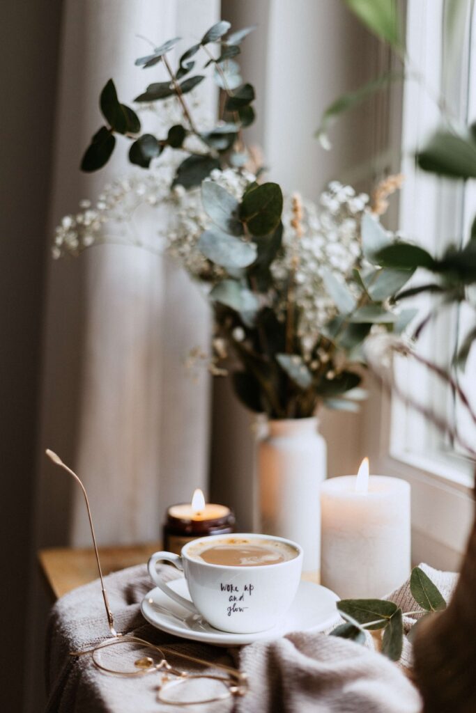 Desk set up with a coffee mug, candles, and a plant. | Dear Self Care