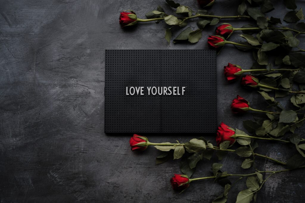 Red roses laying on a table and a box title "Love yourself" | Focusing on self-love